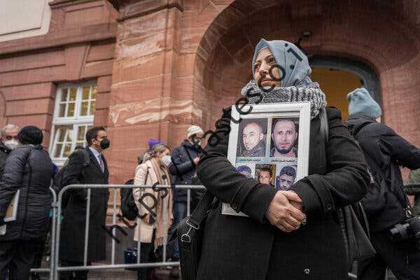 یک واعظ سوری عکس‌هایی از قربانیان جنگ داخلی در بیرون دادگاهی که انور روسلان، مقام سابق سوری در روز پنجشنبه در شهر کوبلنتس آلمان تحت تعقیب قرار داشت، نگه می‌دارد.